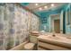 Cozy bathroom featuring blue walls, tub with themed shower curtain, and a white sink vanity, enhanced by a mirrored wall at 351 Windrush Loop, Tarpon Springs, FL 34689