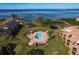 Aerial view of pool with lounge chairs, umbrellas, grilling area and ocean views at waterfront property at 351 Windrush Loop, Tarpon Springs, FL 34689
