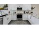 Bright kitchen featuring white cabinets, granite countertops, stainless steel appliances, and wood flooring at 39 Pelican Pl, Belleair, FL 33756