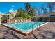 Sparkling community pool surrounded by lounge chairs, lush landscaping, and a pergola for shaded relaxation at 39 Pelican Pl, Belleair, FL 33756