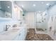 Light and airy bathroom with double vanity, pebble flooring, and glass enclosed shower at 4830 Osprey S Dr # 305, St Petersburg, FL 33711