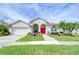 Charming single-story home featuring a red front door and a well-manicured front lawn and landscaping at 9511 Laurel Ledge Dr, Riverview, FL 33569