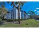 Stylish condominium building with lush front lawn and verdant palms under a vibrant blue sky at 1182 Pine Ridge W Cir # B1, Tarpon Springs, FL 34688