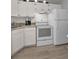 Well-lit kitchen with white appliances, granite countertops, and new laminate flooring at 1182 Pine Ridge W Cir # B1, Tarpon Springs, FL 34688