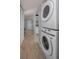 Hallway laundry area with a stacked washer and dryer and wood-look flooring at 1182 Pine Ridge W Cir # B1, Tarpon Springs, FL 34688