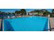 Community pool with lounge chairs surrounded by mature landscaping and building under clear blue skies at 1182 Pine Ridge W Cir # B1, Tarpon Springs, FL 34688