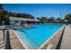 Community pool with hot tub, lounge chairs and tables surrounded by mature landscaping under clear blue skies at 1182 Pine Ridge W Cir # B1, Tarpon Springs, FL 34688