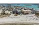 An aerial view showcases beachfront condos, sparkling waters, and white sandy beaches, ideal for relaxation at 12924 Gulf Blvd # 110, St Petersburg, FL 33708
