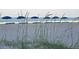 Scenic beach view with sand dunes, sea oats, and blue beach umbrellas facing the ocean at 12924 Gulf Blvd # 110, St Petersburg, FL 33708
