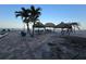 Community area with tiki huts, palm trees, and seating by the beach at 12924 Gulf Blvd # 110, St Petersburg, FL 33708