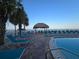 Relaxing poolside area with lounge chairs, a tiki hut, and palm trees, steps from the beach at 12924 Gulf Blvd # 110, St Petersburg, FL 33708