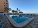 Inviting rectangular pool with palm trees, lounge chairs, and a tiki hut overlooking the beach at 12924 Gulf Blvd # 110, St Petersburg, FL 33708