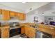 Cozy kitchen with stainless steel appliances, wood cabinetry, and an open counter to the living area at 16143 Rambling Vine E Dr, Tampa, FL 33624