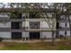 Building exterior showcasing three floors, visible screened in balcony, and mature trees at 2650 Countryside Blvd # F209, Clearwater, FL 33761