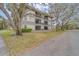 Side exterior of the building surrounded by mature trees and green grass at 2650 Countryside Blvd # F209, Clearwater, FL 33761