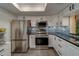 Kitchen with modern stainless steel appliances, white cabinets, and a vibrant blue backsplash at 2650 Countryside Blvd # F209, Clearwater, FL 33761