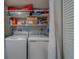 Functional laundry area with a side-by-side washer and dryer and ample shelving for storage at 2650 Countryside Blvd # F209, Clearwater, FL 33761