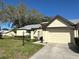 Charming home exterior featuring a well-maintained lawn, mature landscaping, and an attached two-car garage at 3497 Birchwood Ct, Palm Harbor, FL 34684