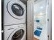 Neat laundry area with a stacked washer/dryer, adjacent to a view of a clean bathroom with a shower-tub combo and blue accents at 4450 Gulf Blvd # 303, St Pete Beach, FL 33706