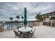 Relaxing outdoor dining on the patio area with seating for four, umbrellas, and lovely views of the ocean and palm trees at 4450 Gulf Blvd # 303, St Pete Beach, FL 33706
