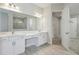 Well-lit bathroom with double vanity, white cabinetry, large mirrors, and tiled shower at 4535 Foley Grove Dr, Valrico, FL 33596