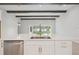 Modern kitchen island boasts white cabinetry, stainless steel appliances, and rustic wooden beam ceiling at 4535 Foley Grove Dr, Valrico, FL 33596