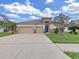 Charming home showcasing a three car garage, a vibrant blue front door, and a well-kept lawn at 4644 Braesgate Ct, Land O Lakes, FL 34639
