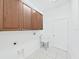 Functional laundry room with upper cabinets, a utility sink, and white tiled flooring at 4644 Braesgate Ct, Land O Lakes, FL 34639