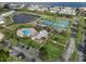 Aerial view of large community swimming pool and tennis courts near a calm lake at 5075 Starfish Se Dr # B, St Petersburg, FL 33705