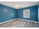 Bright blue bedroom featuring a modern fan, window letting in natural light, and gray wood floors at 5075 Starfish Se Dr # B, St Petersburg, FL 33705