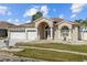 Charming home featuring a well-manicured front lawn, a three car garage and a beautiful arched entryway at 5117 Spectacular Bid Dr, Wesley Chapel, FL 33544