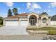 Home with a two-car garage, manicured landscaping, and double door entrance framed by stately columns at 5117 Spectacular Bid Dr, Wesley Chapel, FL 33544