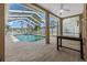 A covered screened in pool with a ceiling fan and a table in an attached room at 5117 Spectacular Bid Dr, Wesley Chapel, FL 33544