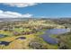 Expansive aerial view showcasing a serene lake surrounded by lush greenery, farmland, and scattered homes at 6850 Ripple Pond Loop, Zephyrhills, FL 33541