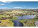 Picturesque aerial of a tranquil lake surrounded by lush greenery and open fields at 6850 Ripple Pond Loop, Zephyrhills, FL 33541
