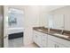 Bathroom featuring a double sink vanity with granite countertops and a large mirror, leading to the bedroom at 6850 Ripple Pond Loop, Zephyrhills, FL 33541