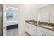 Modern bathroom with double sink vanity and granite countertops, leading to the bedroom at 6850 Ripple Pond Loop, Zephyrhills, FL 33541