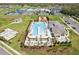 Aerial shot of the community pool area featuring a T-shaped pool, sun loungers, and manicured landscaping at 6850 Ripple Pond Loop, Zephyrhills, FL 33541