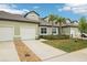 Beautiful townhome exterior featuring attached garage, stone accents, and tropical landscaping at 6850 Ripple Pond Loop, Zephyrhills, FL 33541