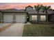 Charming exterior showcasing a two-car garage, well-maintained lawn and a tropical palm tree at 6850 Ripple Pond Loop, Zephyrhills, FL 33541