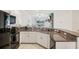 Well-lit kitchen features granite countertops, white cabinets, and modern black appliances, seamlessly flowing into the living room at 6850 Ripple Pond Loop, Zephyrhills, FL 33541