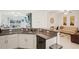Open kitchen with granite countertops and white cabinetry, connecting to a living area and outdoor patio at 6850 Ripple Pond Loop, Zephyrhills, FL 33541