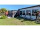 Landscaped backyard with lush green lawn, tropical plants, and a screened-in lanai at 7309 Islander Ln, Hudson, FL 34667