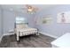 Comfortable bedroom featuring a ceiling fan, gray wood-look floors, and two windows allowing ample natural light at 7309 Islander Ln, Hudson, FL 34667