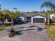 Charming one-story home featuring lush tropical landscaping, a spacious driveway, and a convenient two-car garage at 7309 Islander Ln, Hudson, FL 34667
