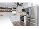 Bright kitchen with stainless steel appliances, ample counter space, and floating wood shelves for storage at 7309 Islander Ln, Hudson, FL 34667
