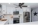 Modern kitchen with white cabinets, stainless steel appliances, subway tile backsplash, and a stylish ceiling fan at 7309 Islander Ln, Hudson, FL 34667