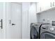 Functional laundry room with modern washer and dryer units, and white cabinetry at 7309 Islander Ln, Hudson, FL 34667