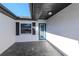 Covered front patio area with a vibrant blue door, window with shutters, and slate tile floor at 7309 Islander Ln, Hudson, FL 34667