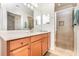 Well-lit bathroom featuring wood vanity cabinets, a walk-in shower, and a large mirror at 8403 Grand Estuary Trl # 204, Bradenton, FL 34212
